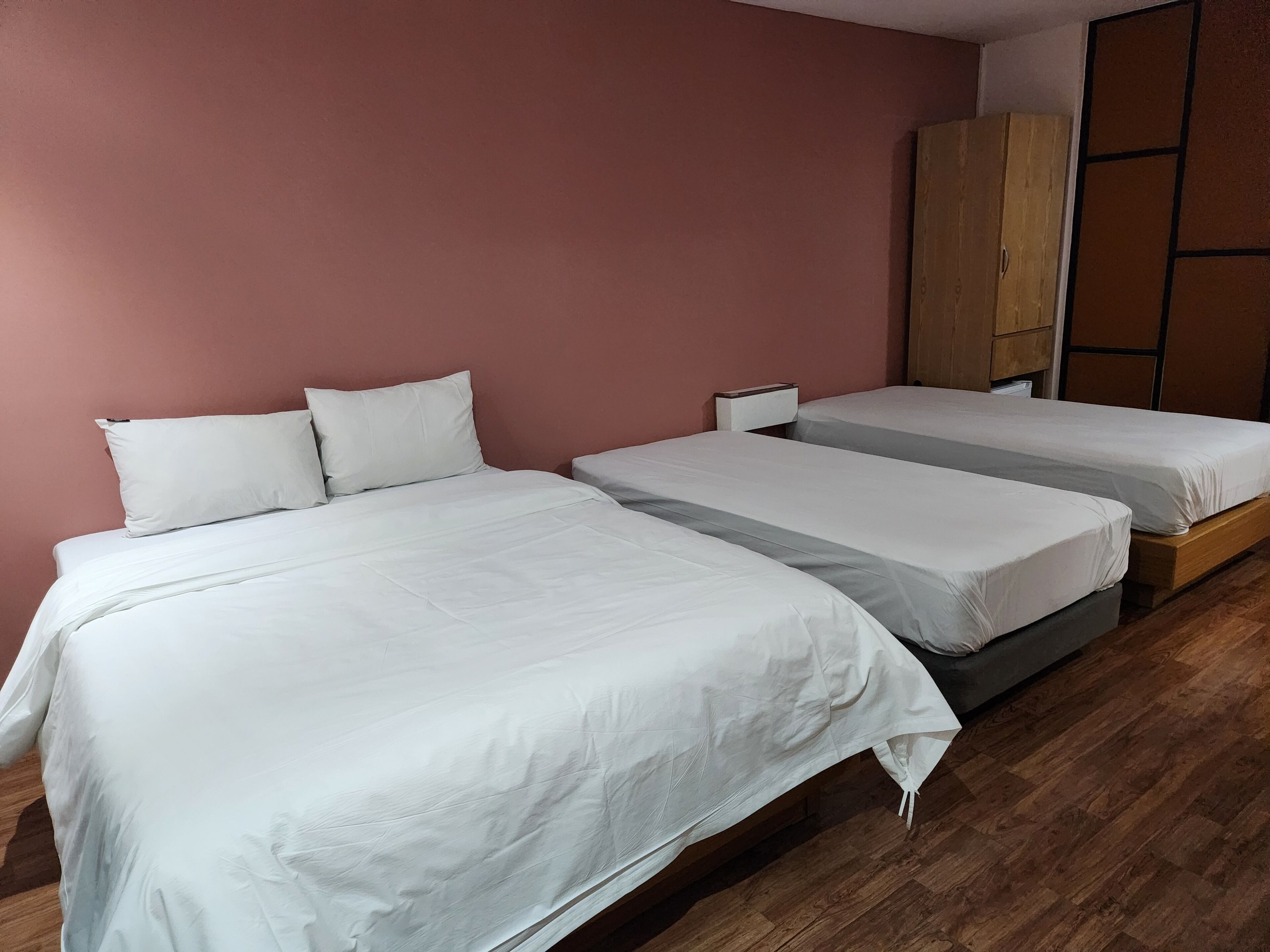 A hotel room with two beds, a wardrobe, and a wooden floor.
