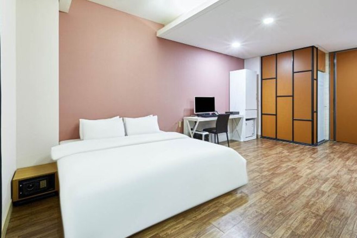 Una habitación de hotel moderna con una cama grande, un escritorio y un armario.