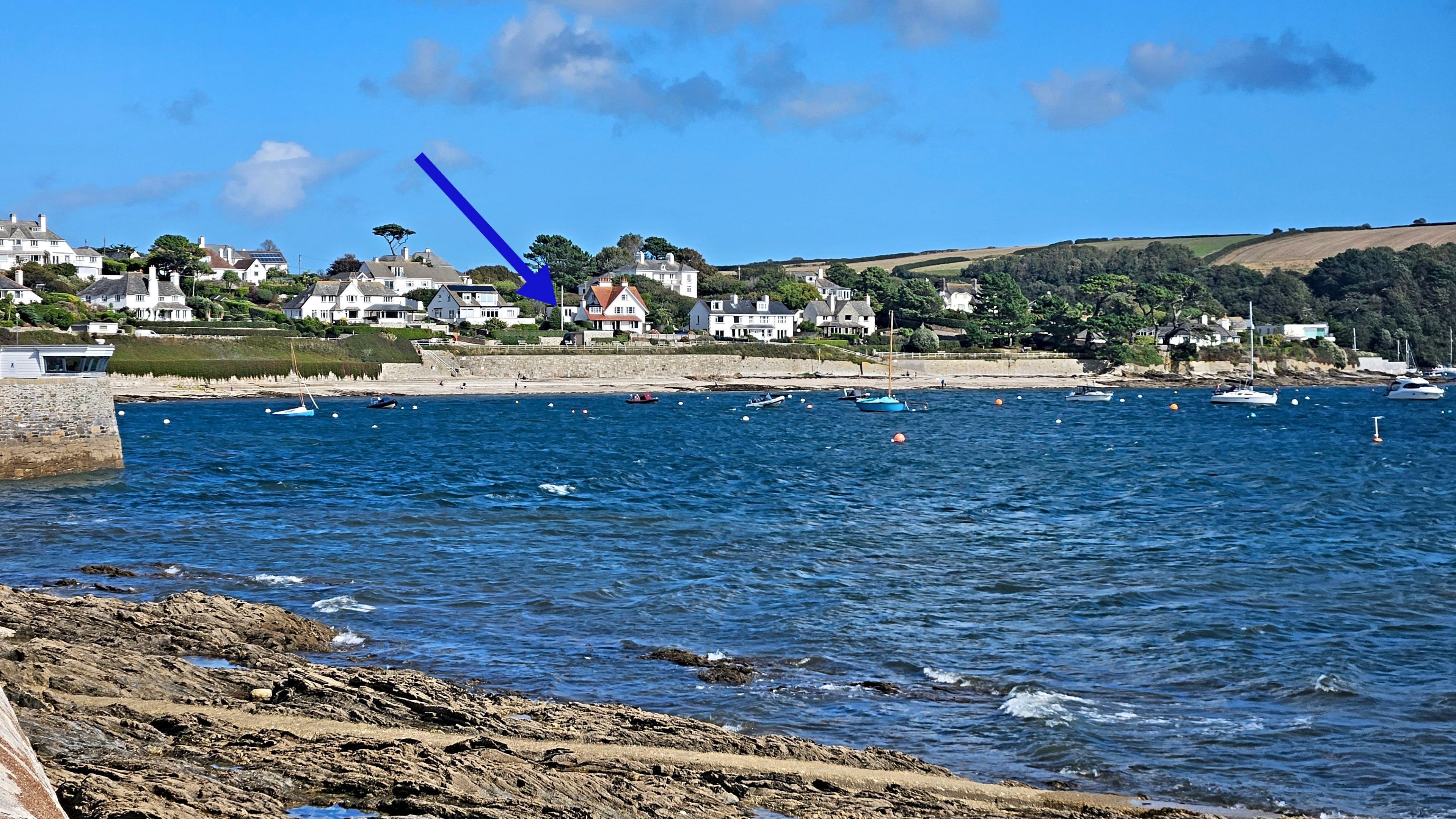 A coastal town with a rocky shoreline, calm sea, and houses along the coast.
