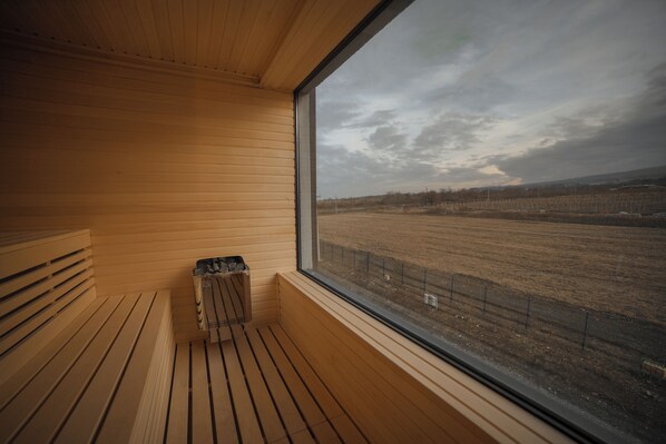 A sauna room with a wooden bench and a window overlooking a field. - Matilda Signature Villas (Telavi)