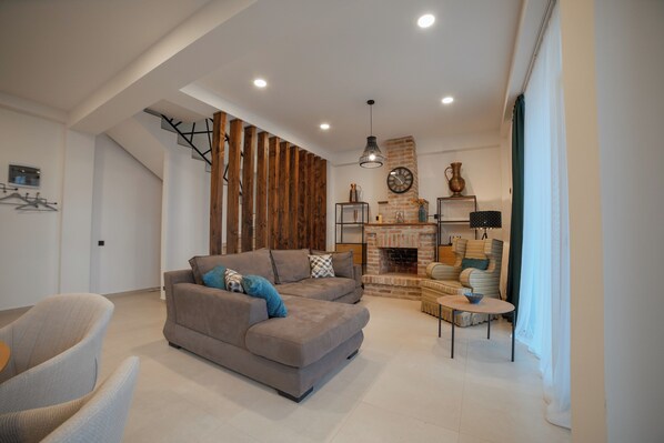 A modern living room with a sofa, armchairs, a coffee table, and a fireplace. - Matilda Signature Villas (Telavi)