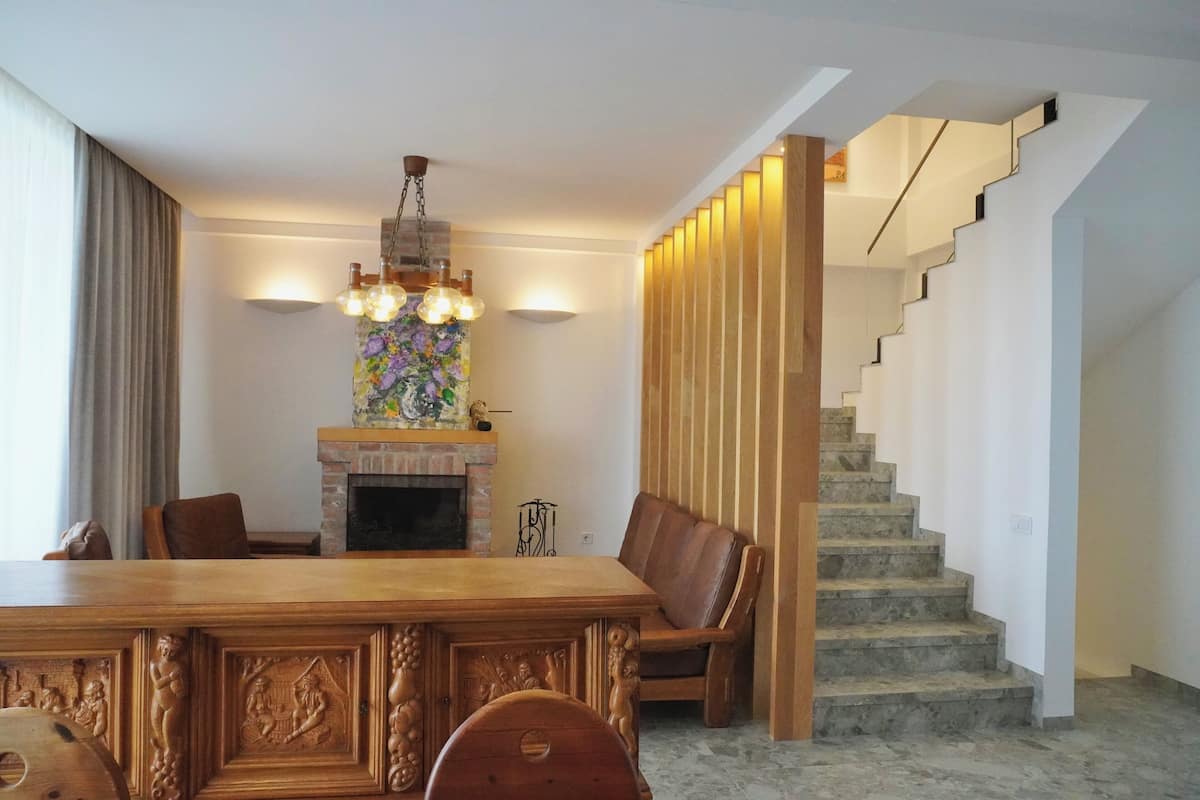 A dining area with a wooden table and chairs, a fireplace, and a staircase.