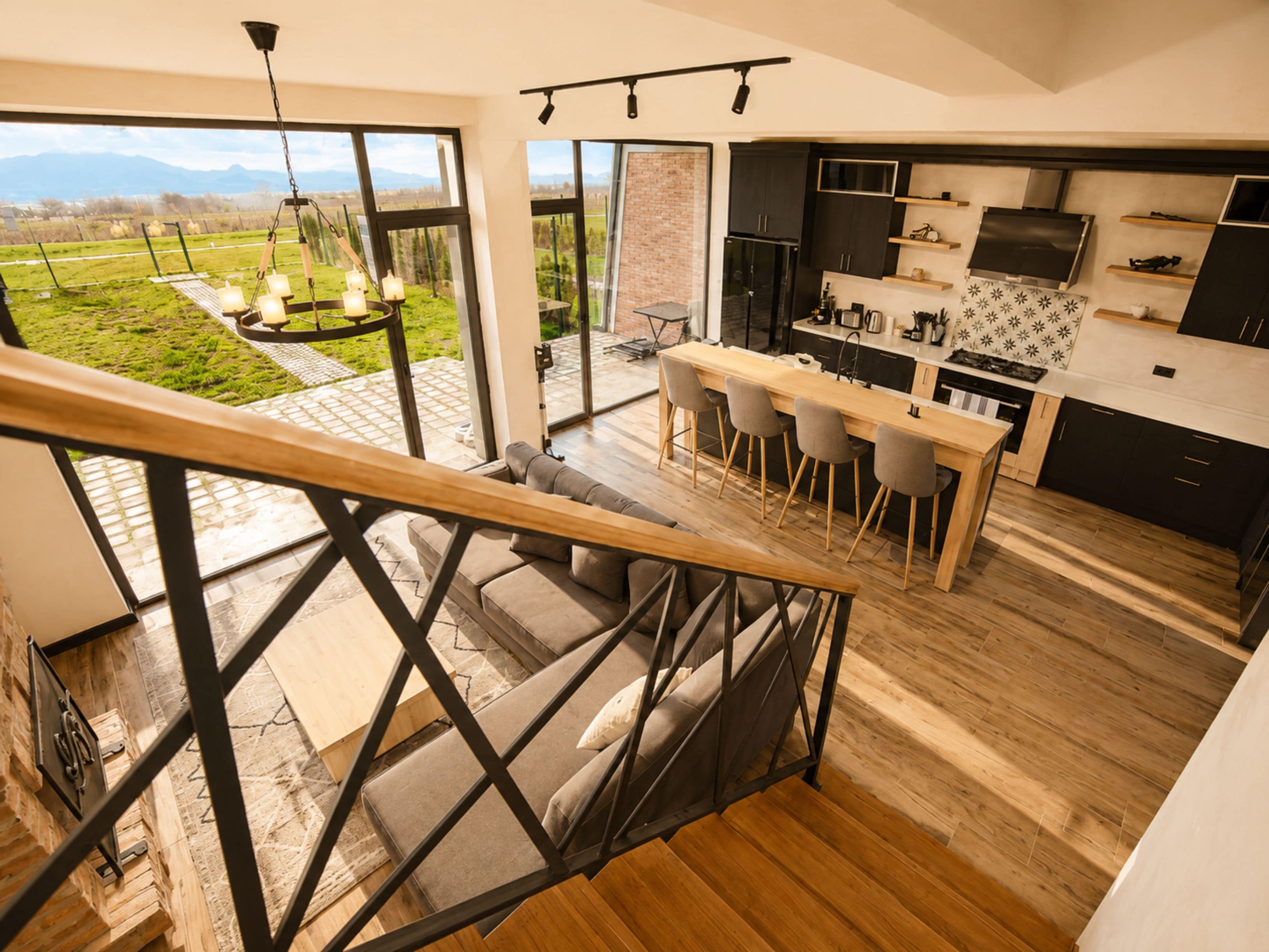A modern kitchen with a bar area, large windows, and a view of a green landscape.