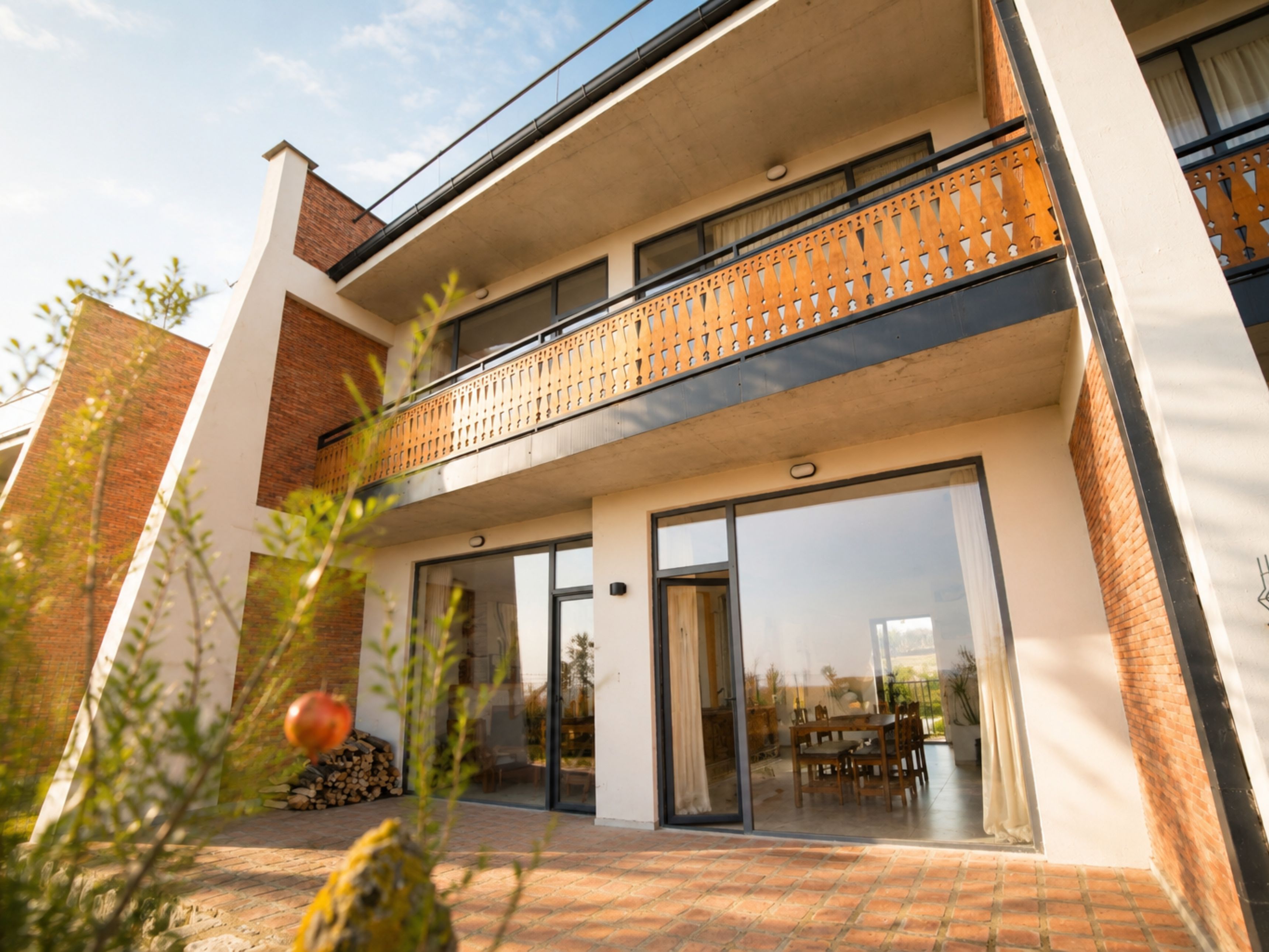 A modern two-story building with a balcony, large glass doors, and a brick facade.