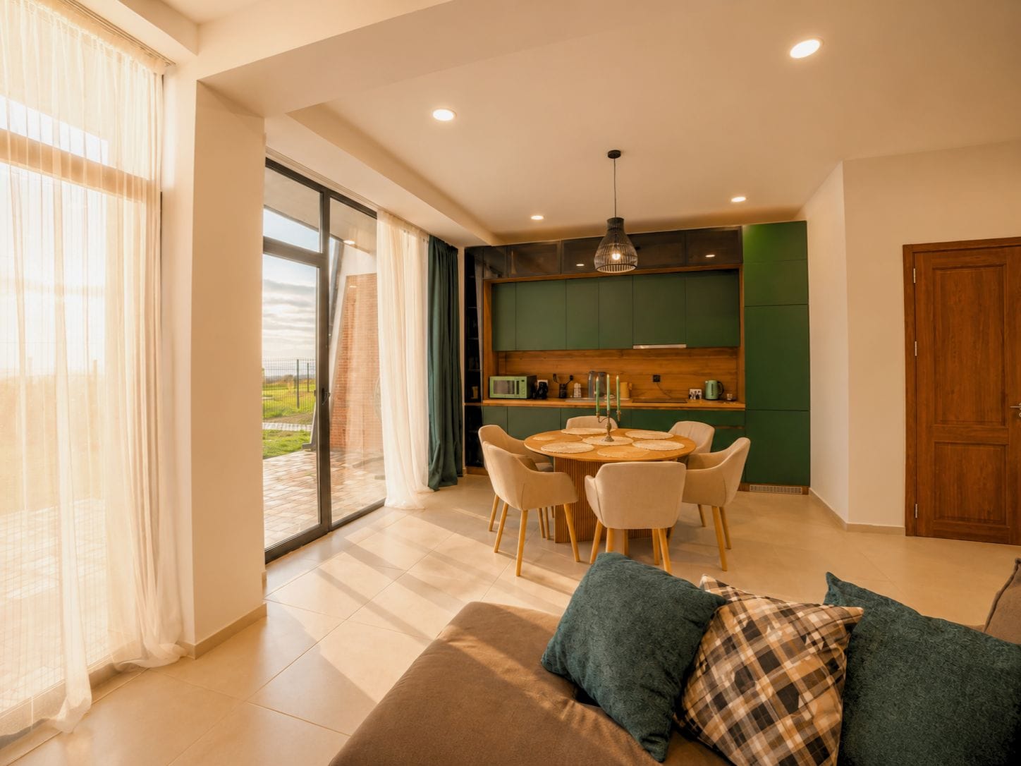 Una sala de estar moderna con un sofá, una mesa de comedor con sillas y una zona de cocina con armarios verdes.
