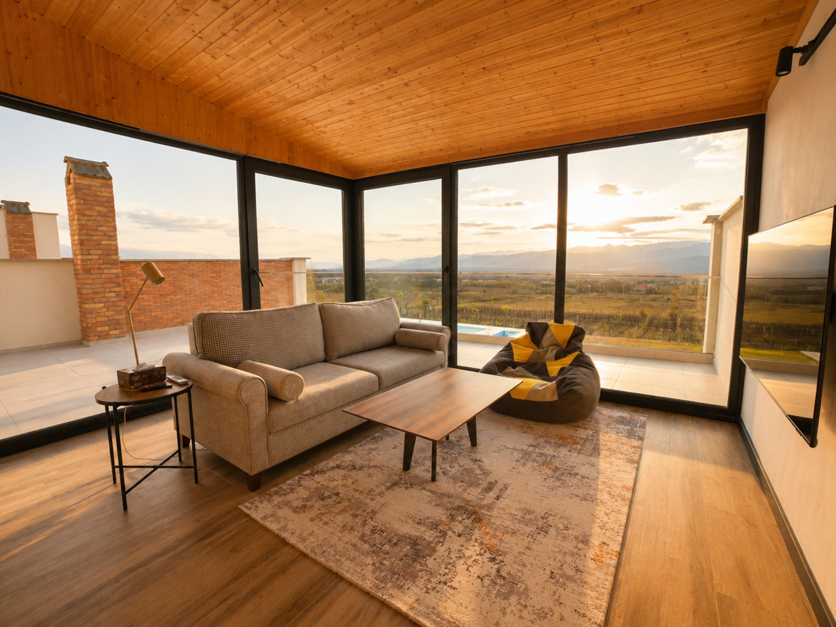 Una sala de estar moderna con un sofá, una mesa de centro y vistas al campo a través de amplios ventanales.