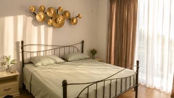 A bedroom with a metal bed frame, a bedside table with a lamp, and a wall-mounted decorative piece.