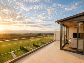 A modern balcony with a glass door, a sofa, and a TV. - Matilda Signature Villas (Telavi)