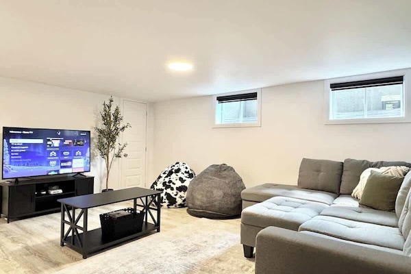 Détendez-vous avec style grâce à un sectionnel élégant, des poufs poires et une télévision intelligente pour vous divertir!