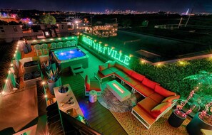 A rooftop patio with a hot tub, outdoor seating, and a neon sign reading "Nashville."