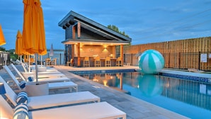 A pool area with lounge chairs, a bar, and a wooden fence. - Lux Nash Escape•11 Beds•Hot Tub•Game Room + Pool+ Pickleball (Nashville)