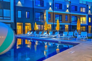 Um hotel moderno com área de piscina, espreguiçadeiras e guarda-sóis.