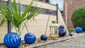 Blauwe decoratieve vazen, een potplant en een lantaarn op een stenen pad.