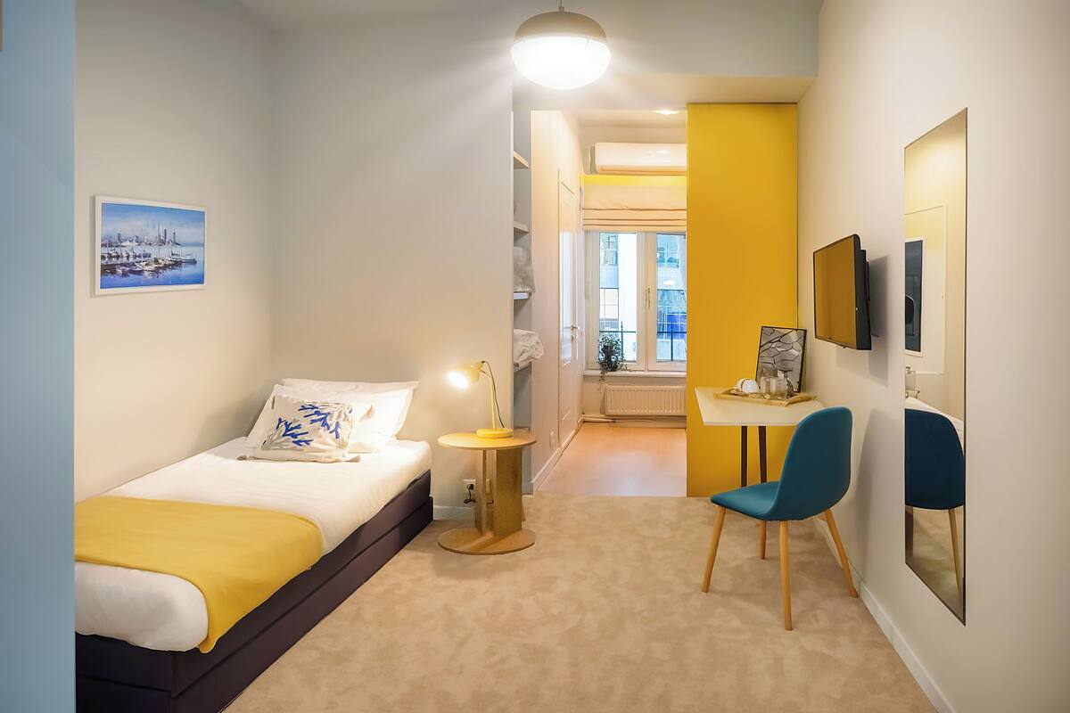 Habitació d'hotel moderna amb llit, làmpada de nit, cadira i obra d'art a les parets.