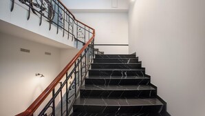 A staircase with black marble steps and a wooden handrail, leading to an upper floor with a bike rack. - HB Freeze Inn (Tbilisi)