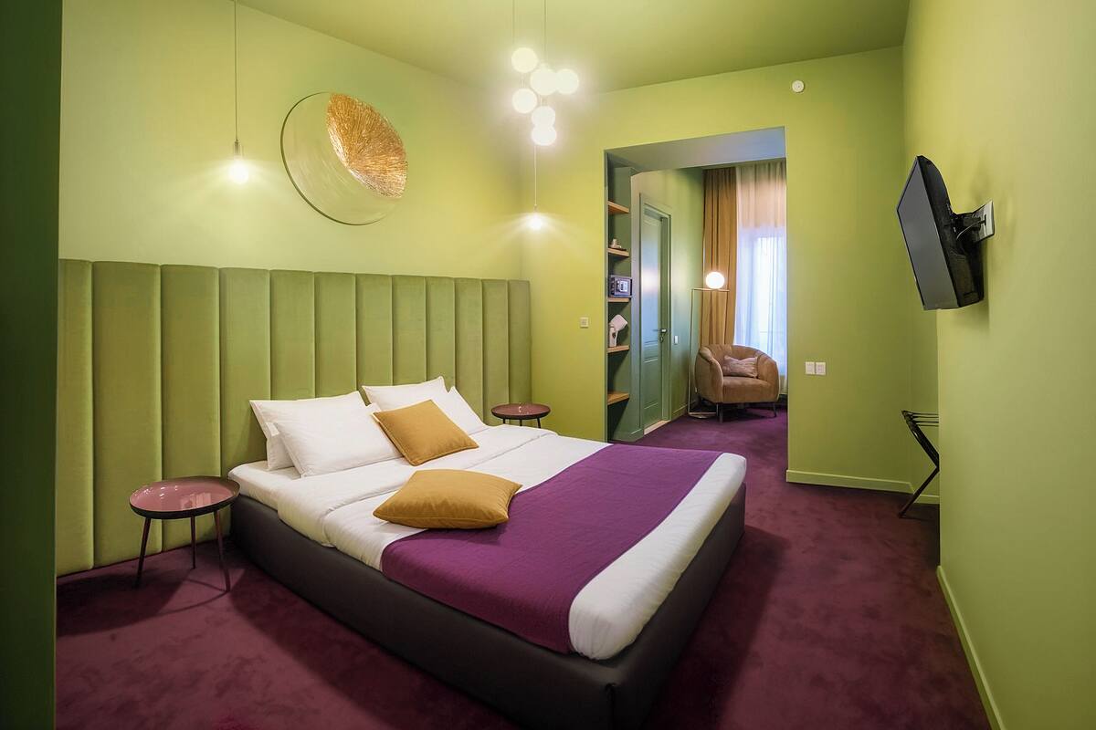 Habitació d'hotel moderna amb un llit gran, televisió de pantalla plana, taula auxiliar petita i un mirall a la paret.