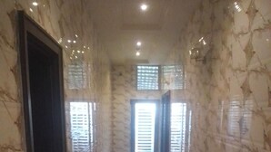 Un couloir dallé de marbre, avec une porte à gauche et une fenêtre à droite.
