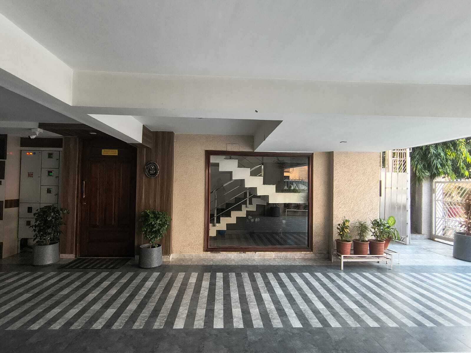 A modern building entrance with a staircase, potted plants, and a striped floor.