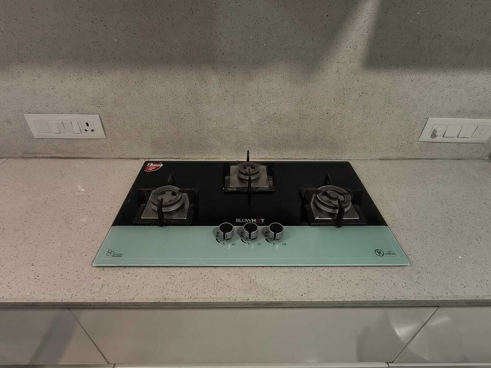 Una cocina con fogones negros y salpicadero verde.
