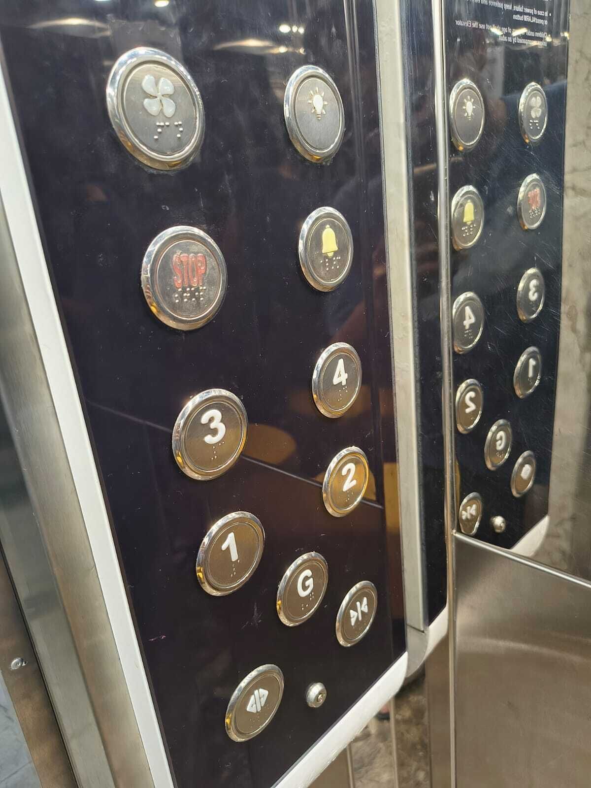 Panel de control de ascensor con botones numerados del 1 al 4, un botón de parada y un botón de timbre.