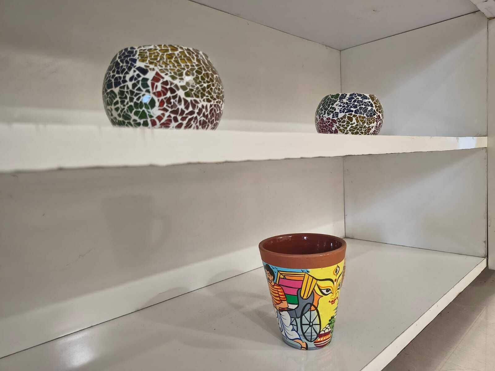 A shelf with three ceramic vases and one painted mug.