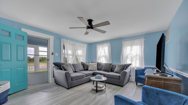 A living room with a grey sectional sofa, a blue armchair, a coffee table, and a TV on a wooden cabinet. - 212 E. Savannah Road. Lewes, Delaware (Lewes)