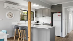 A modern kitchen with a central island, grey cabinetry, and a white refrigerator. - OPI San Remo with water views (San Remo)