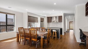 Une cuisine moderne avec des meubles en bois, un îlot central et un coin repas doté de chaises en bois.