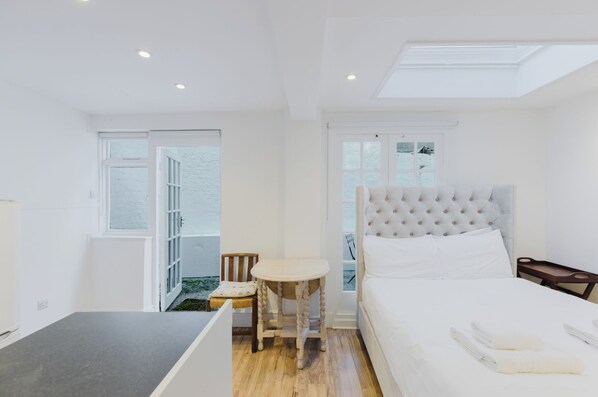 A modern bedroom with a bed, bedside table, and a small table with a chair.