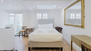 A modern bedroom with a large bed, a skylight, a mirror, and a view of the outdoors.