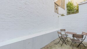 A white brick wall with a small patio area featuring a table and chairs.