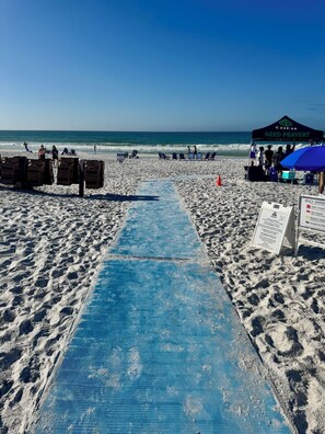 Ein Strand mit einer blauen Matte, die zu einem Zelt führt, auf dem 'NEED PRAYER?' steht.
