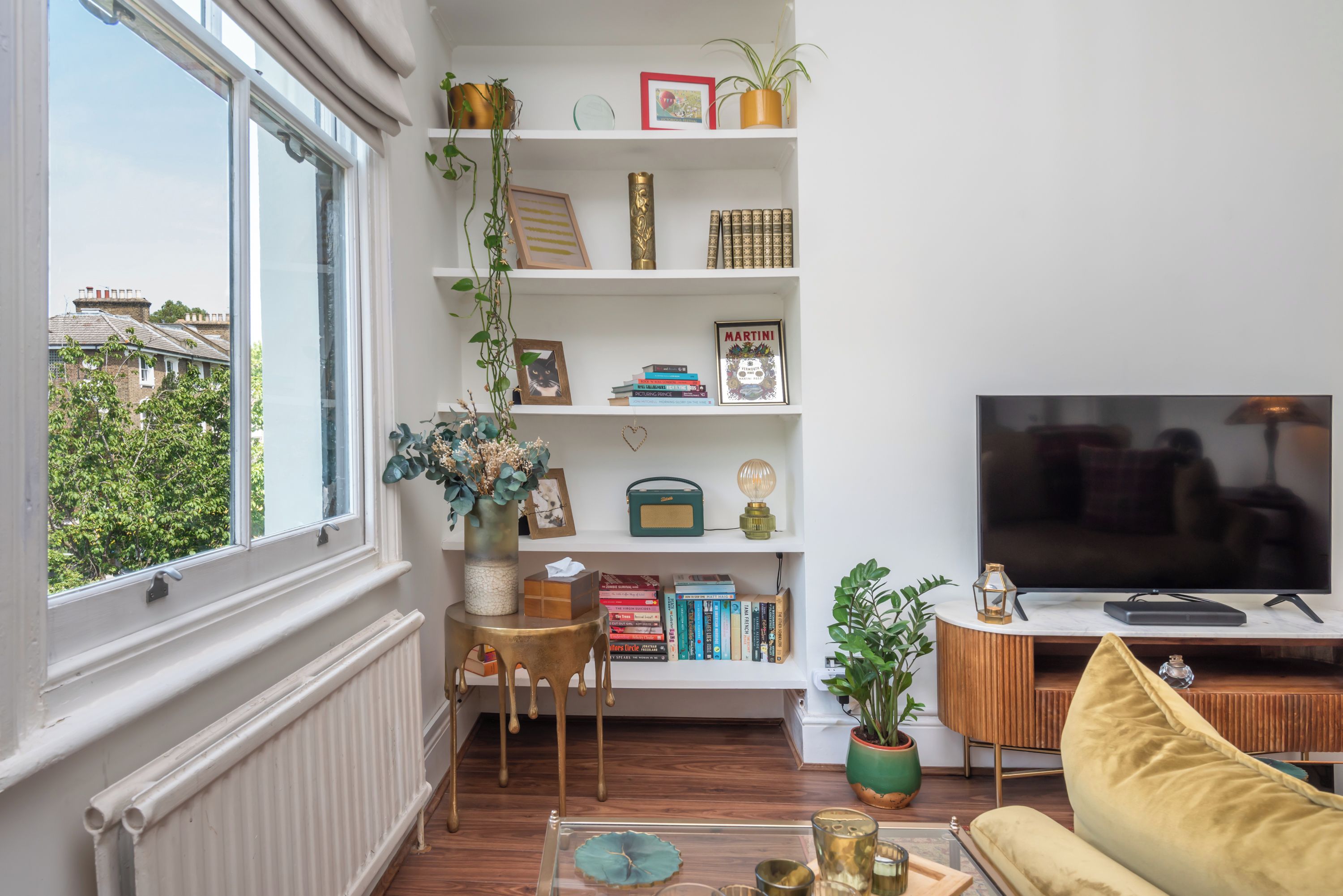 A living room with a large window, a bookshelf, a television, and a sofa.