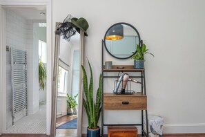 A modern bathroom with a glass shower enclosure, a towel rack, and a mirror with a round frame. - Modern 1BDR with Parking and Shared Garden (Greater London)