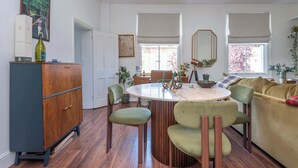 Un coin repas comprenant une table ronde, des chaises, un buffet et un canapé.