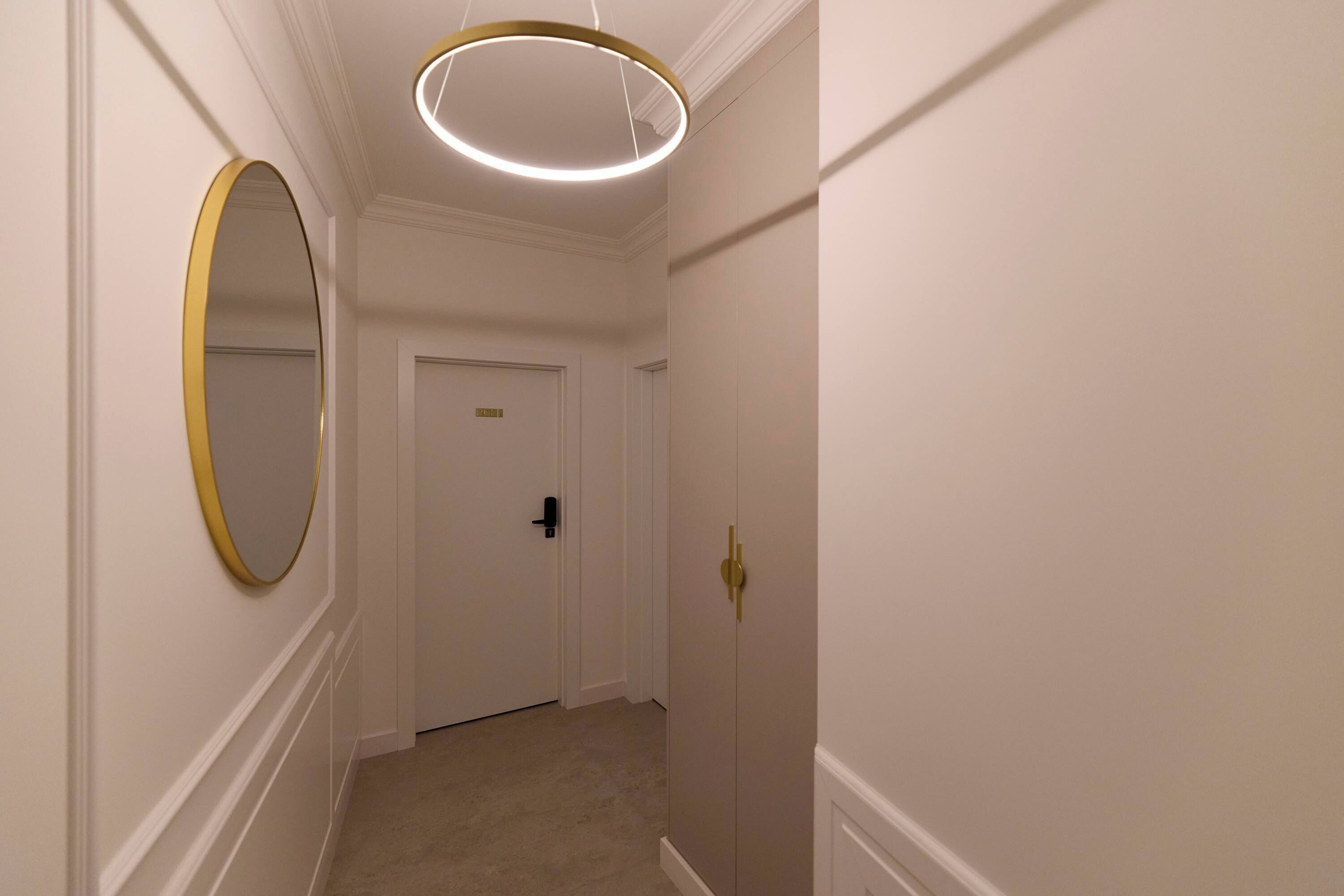 A hallway with a door, a round mirror, and a modern light fixture.
