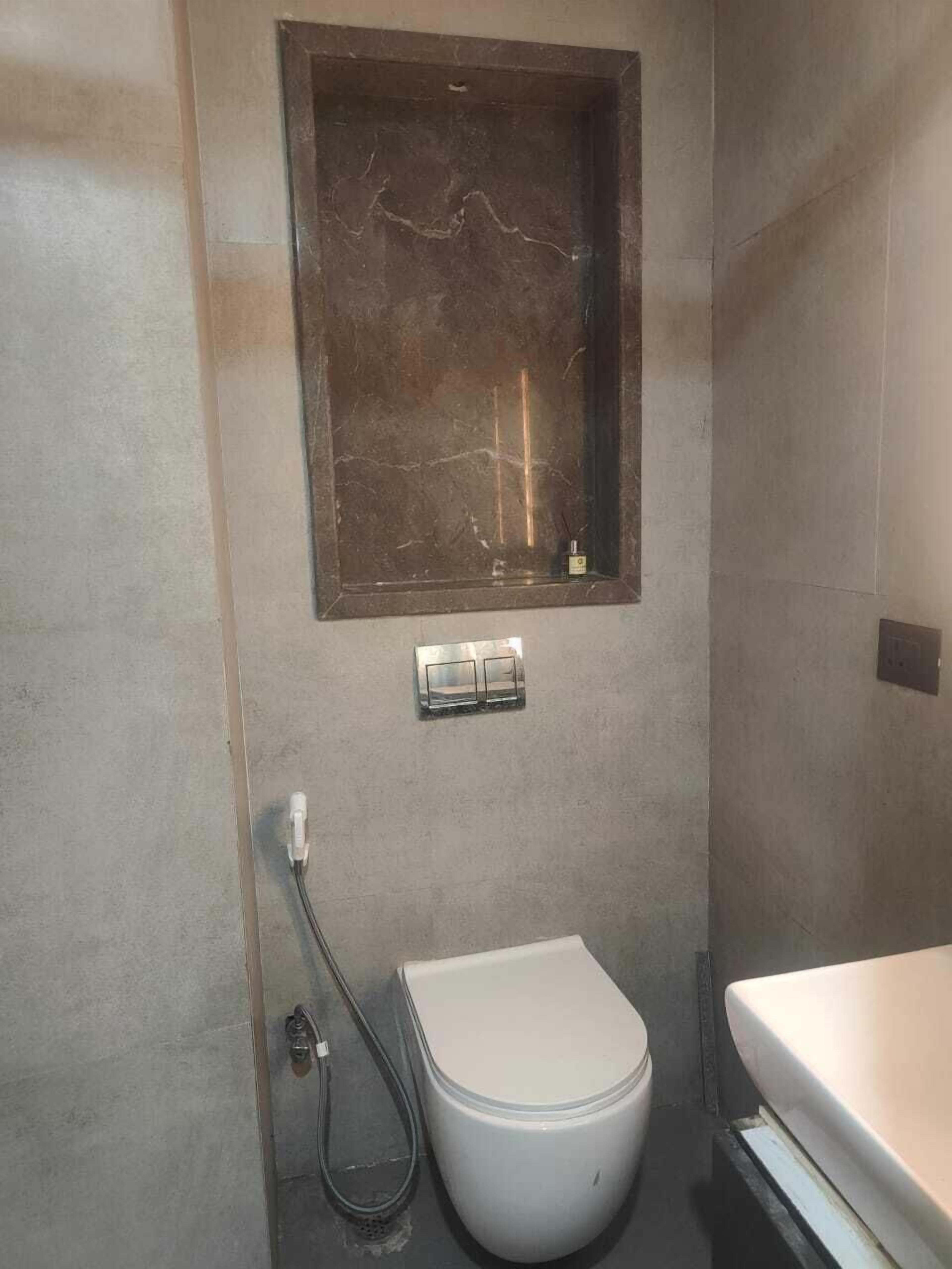 Ein Badezimmer mit Toilette, Duschbereich und Marmorwand.