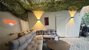 Ett modernt loungeområde med en grå hörnsoffa, ett runt soffbord i trä och en neonskylt.