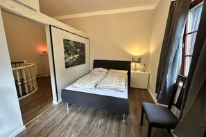 A bedroom with a bed, bedside tables, a chair, a painting, and a window with curtains. - Workshop 17 - Chilling & barbecuing (Treuenbrietzen)