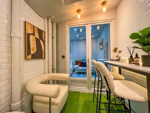 A modern interior with white brick walls, a glass door leading to a living area, and a green artificial turf floor. - UrbanFlat 11 - Cosy king studio near champs Elysees (París)
