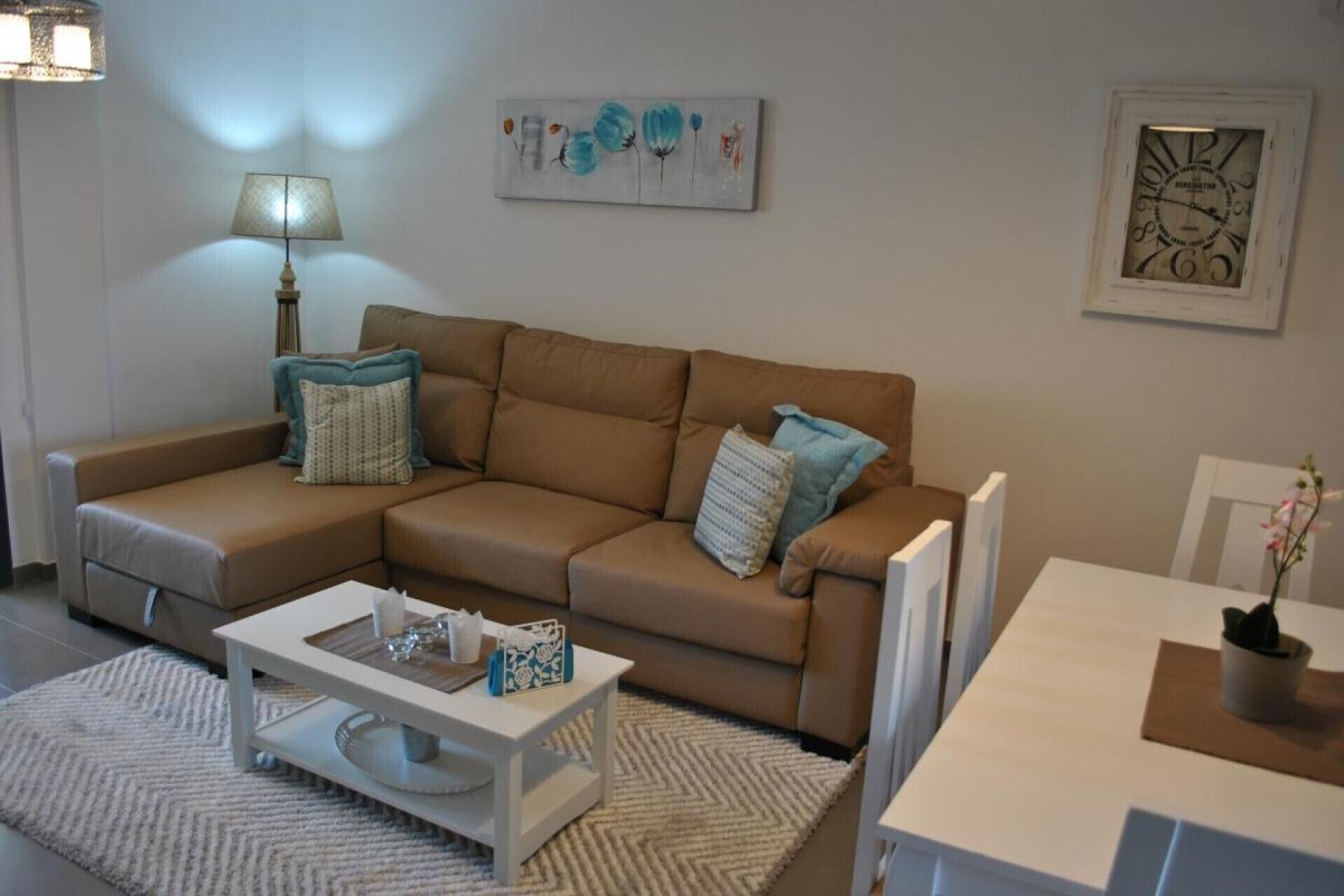 A living room with a brown sofa, a white coffee table, and a lamp.