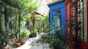 A narrow alleyway with potted plants and a blue building with red trim. - Superb air-conditioned apartment in the center of Paris/Le Marais (Paris)