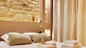 A bed with beige pillows, a bottle of orange juice, and folded towels. - Superb air-conditioned apartment in the center of Paris/Le Marais (Paris)