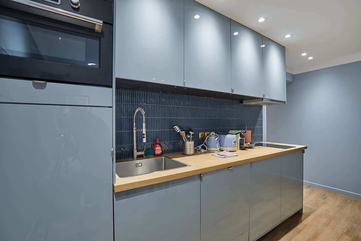 A modern kitchen with grey cabinets, a wooden countertop, and a built-in oven.