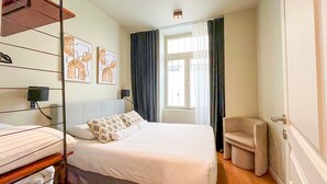 A hotel room with a bed, a chair, a shelf with towels, and artwork on the wall. - 138 - Urban Luxurious Flat in Saint Germain (París)
