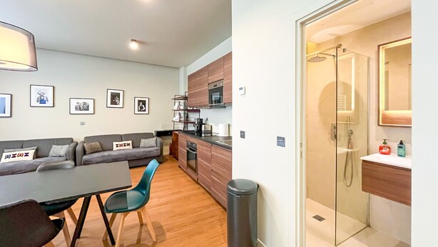 A modern apartment with a dining area, sofa, kitchen, and a glass-enclosed shower. - 138 - Urban Luxurious Flat in Saint Germain (París)