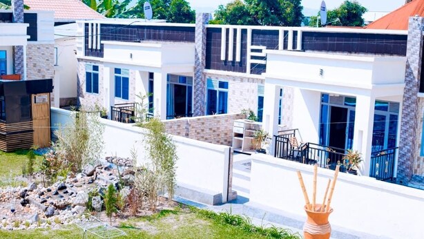 A modern residential complex with multiple two-story houses, featuring large windows, balconies, and a landscaped garden area. - The Moon Crib (Gisenyi)