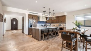 A spacious kitchen with a central island, wooden cabinets, and pendant lighting. - Villa Azulejos, Luxury villa with privacy and breathtaking views (Cabo San Lucas)