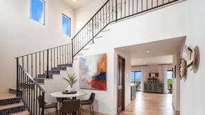 A spacious living area with a staircase, a dining table with chairs, and a view to the outside. - Villa Azulejos, Luxury villa with privacy and breathtaking views (Cabo San Lucas)