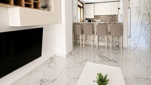 A modern kitchen with white cabinets, a marble backsplash, and a dining area with chairs. - Luxury Penthouse Sunny Terrace by Alma Homes (Los Cristianos)